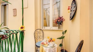 Un pequeño espacio al aire libre con comedor, una mesa lista para el desayuno, una silla, una planta en maceta y un dardo en la pared.