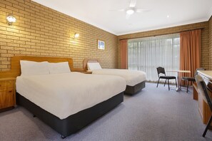 A hotel room with two beds, a desk, and a chair.
