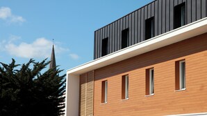 A modern building with a wooden facade and a black upper section. - Brit Hotel Vannes-Theix (Theix-Noyalo)