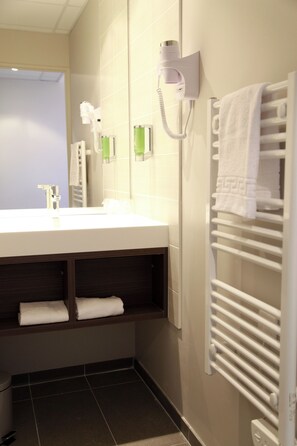 Een badkamer met een wastafel, handdoekhouder en een aan de muur bevestigde haardroger.