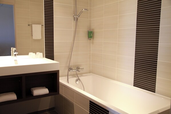 Une salle de bain moderne équipée d’une baignoire, d’une douche et d’un meuble-lavabo avec un miroir.