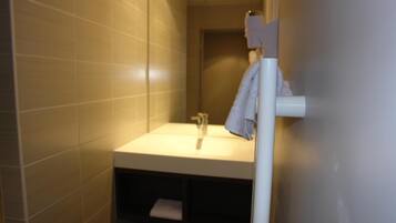 Un baño con un lavamanos, una toalla colgada en un perchero y una puerta que da a otra habitación.