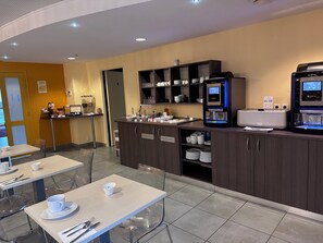 A modern cafe with tables, chairs, a coffee machine, and a self-service beverage station.