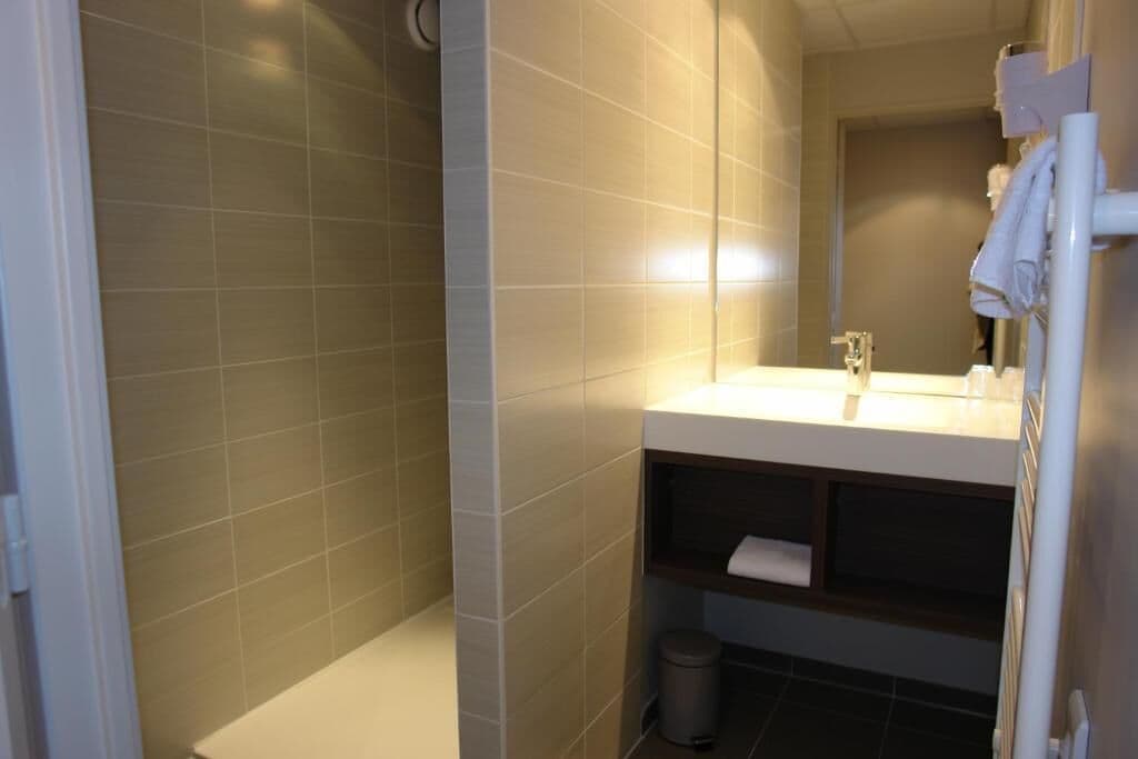 Un baño moderno con ducha, lavamanos y espejo.