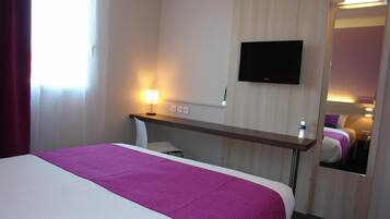 Une chambre d’hôtel avec un lit, un bureau, une télévision et un miroir.