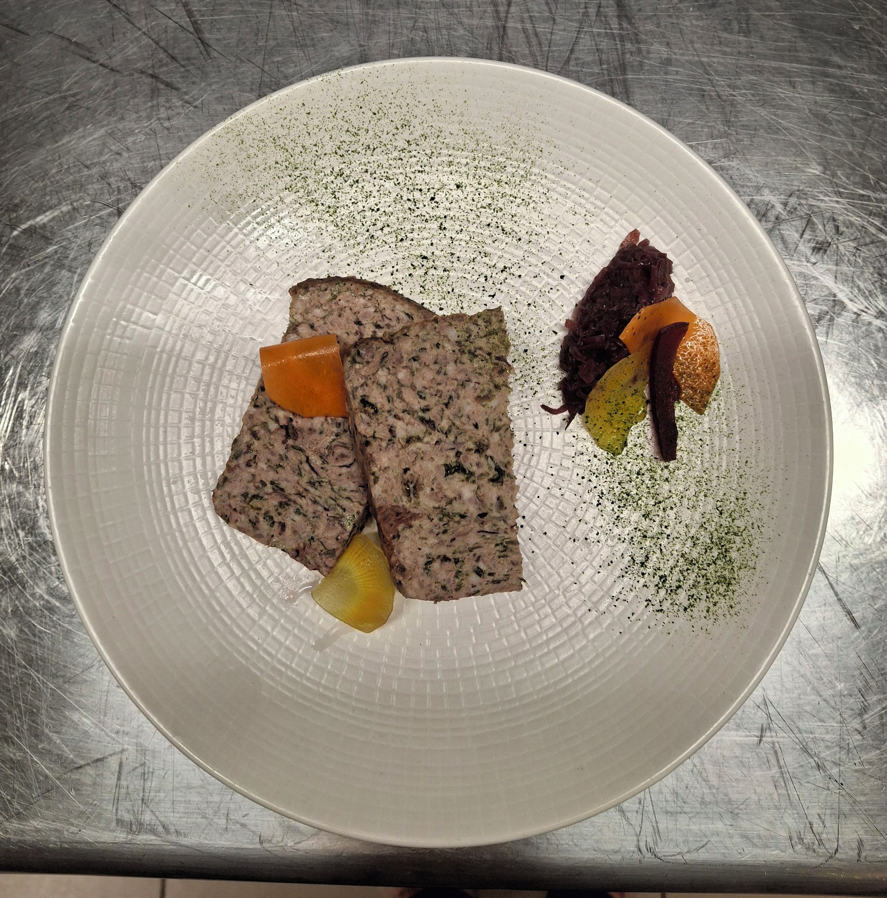 A plate with slices of meat, a piece of orange, and some vegetables on a textured surface.