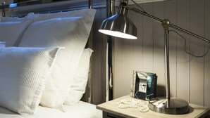 A neatly made bed with white linens, a bedside lamp, and a small bedside table with a picture frame and a decorative item. - Clarendon Cottages (Sassafras)