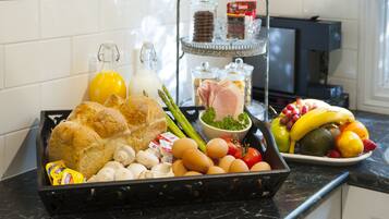 A breakfast tray with bread, eggs, asparagus, tomatoes, and a variety of fruits and vegetables.