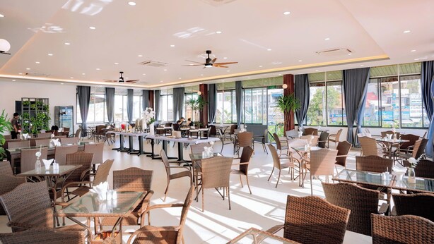 A spacious hotel dining area with wicker furniture, large windows, and ceiling fans. - Song Tien Hotel (My Tho)