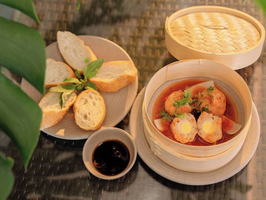 Uma mesa com uma tigela de sopa, pão e uma pequena tigela de molho.