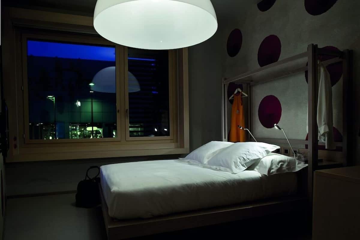 A bedroom with a bed, a window, and a pendant light.