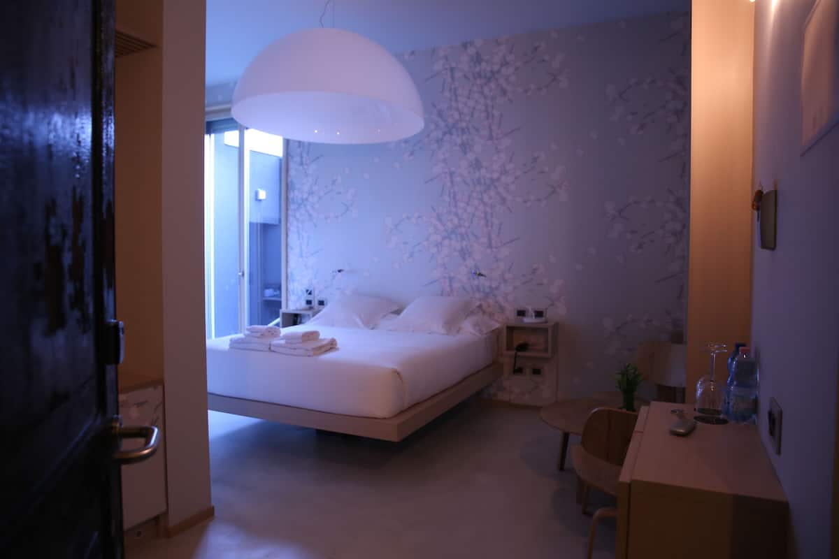 A bedroom with a bed, bedside table, and a desk with a chair.