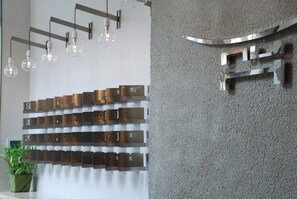 Modern reception area with a minimalist design, featuring a wall-mounted number plate system, ambient lighting, and a touch of greenery.