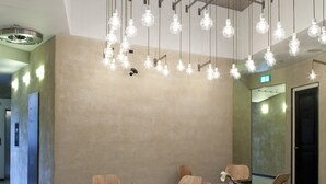 A modern interior with hanging light fixtures, wooden furniture, and a neutral color palette. - NU Hotel (Milan)