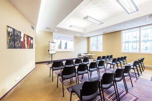 A conference room with rows of chairs, a whiteboard, and a presentation screen.
