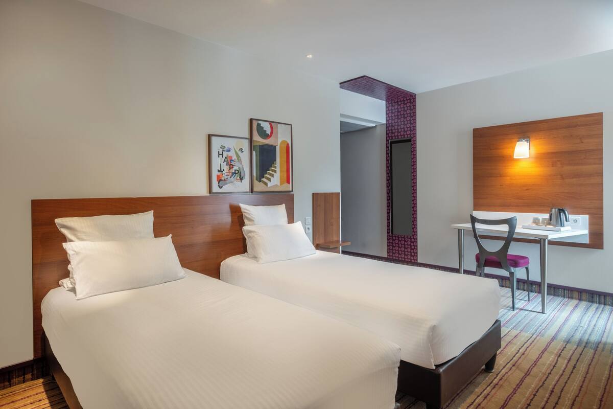 Ein Hotelzimmer mit zwei Betten, einem Schreibtisch und einem Stuhl.