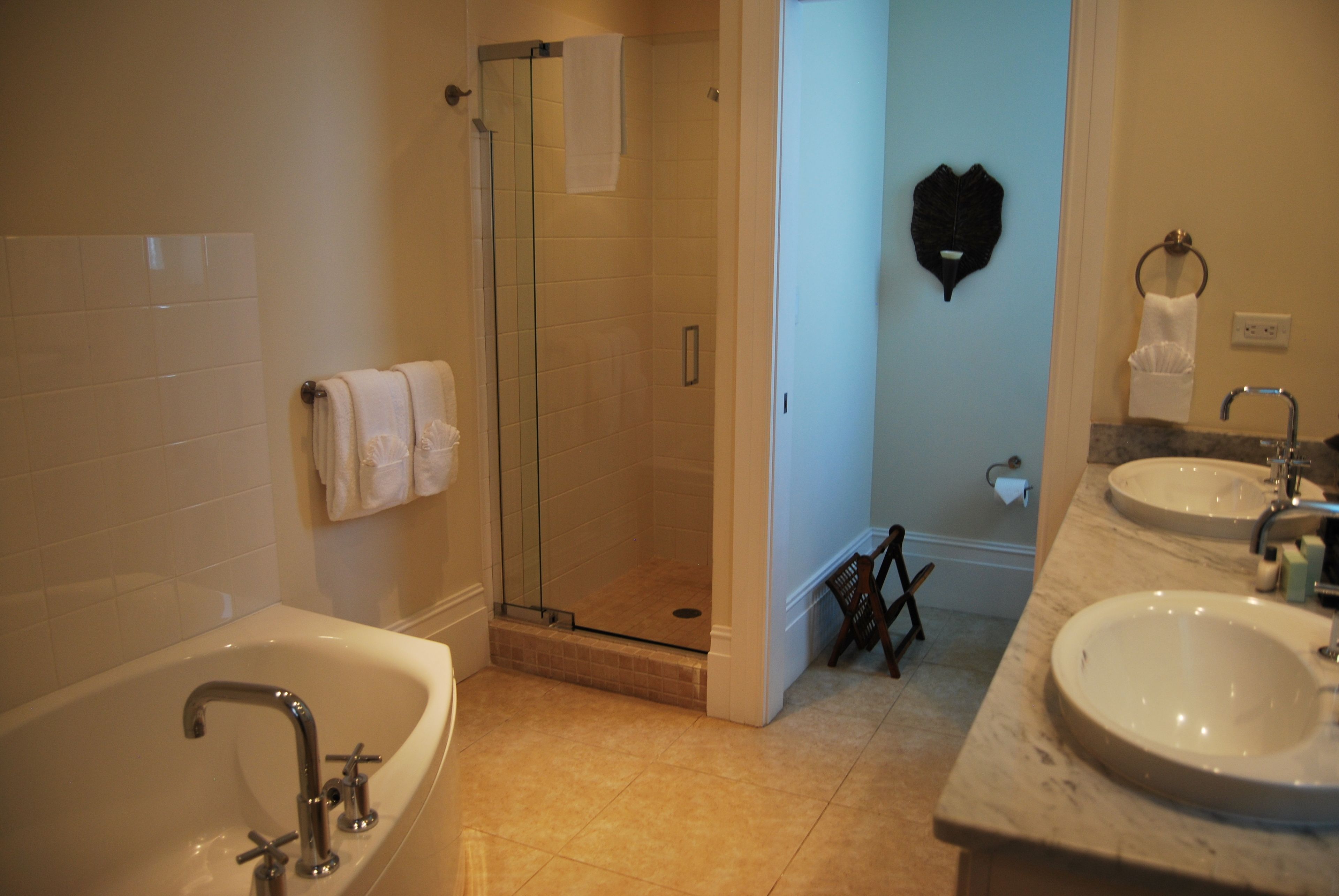 Un baño con bañera, ducha con mampara de vidrio y dos lavamanos.