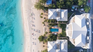 A resort with a pool, beach, and multiple buildings with a unique geometric roof design. - Caribbean Club Luxury Condo Hotel (Seven Mile Beach)
