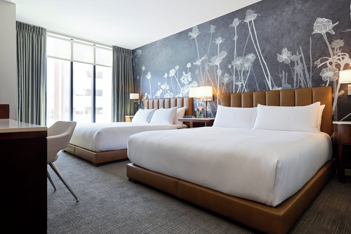 Habitación de hotel con dos camas, un escritorio y una silla.