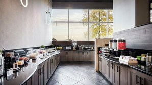 A modern kitchen with a long counter, various food items, and a large window.