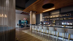 A modern bar area with a wooden ceiling, patterned floor, and bar stools.