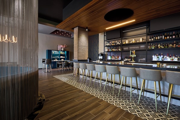 A modern bar area with a wooden ceiling, patterned floor, and bar stools.
