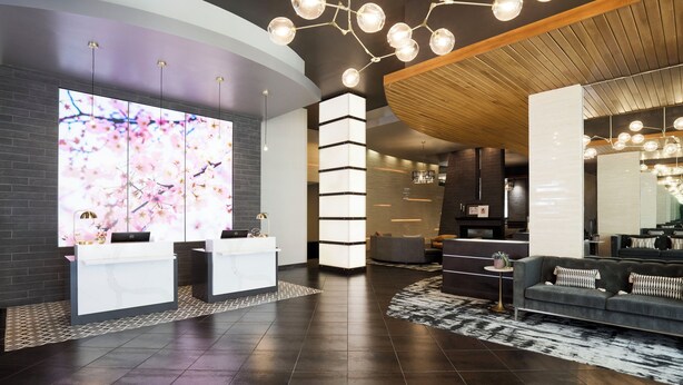 A modern lobby with a reception desk, seating area, and a large digital display.
