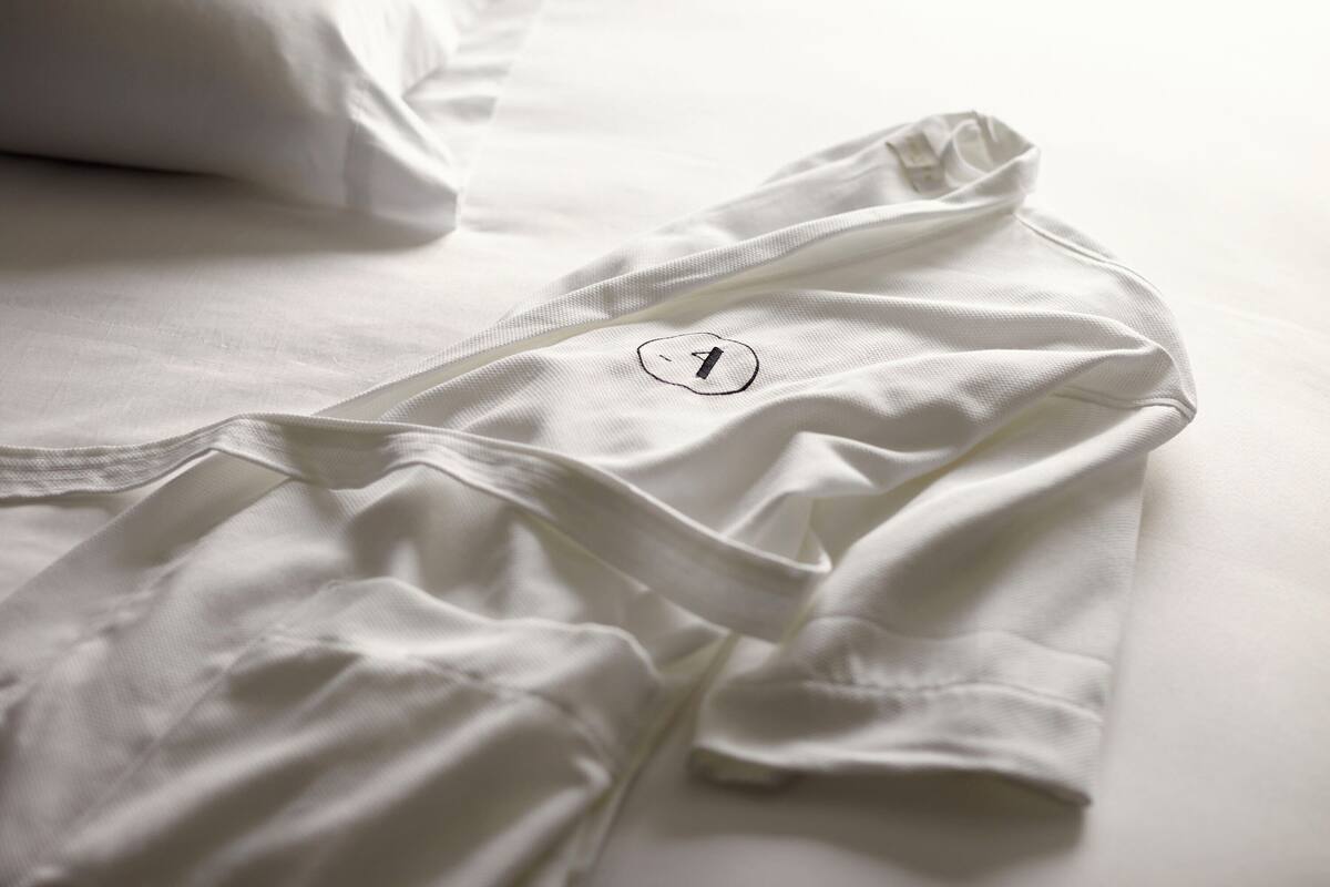 Una cama bien tendida con ropa blanca y una etiqueta visible con el número 1.