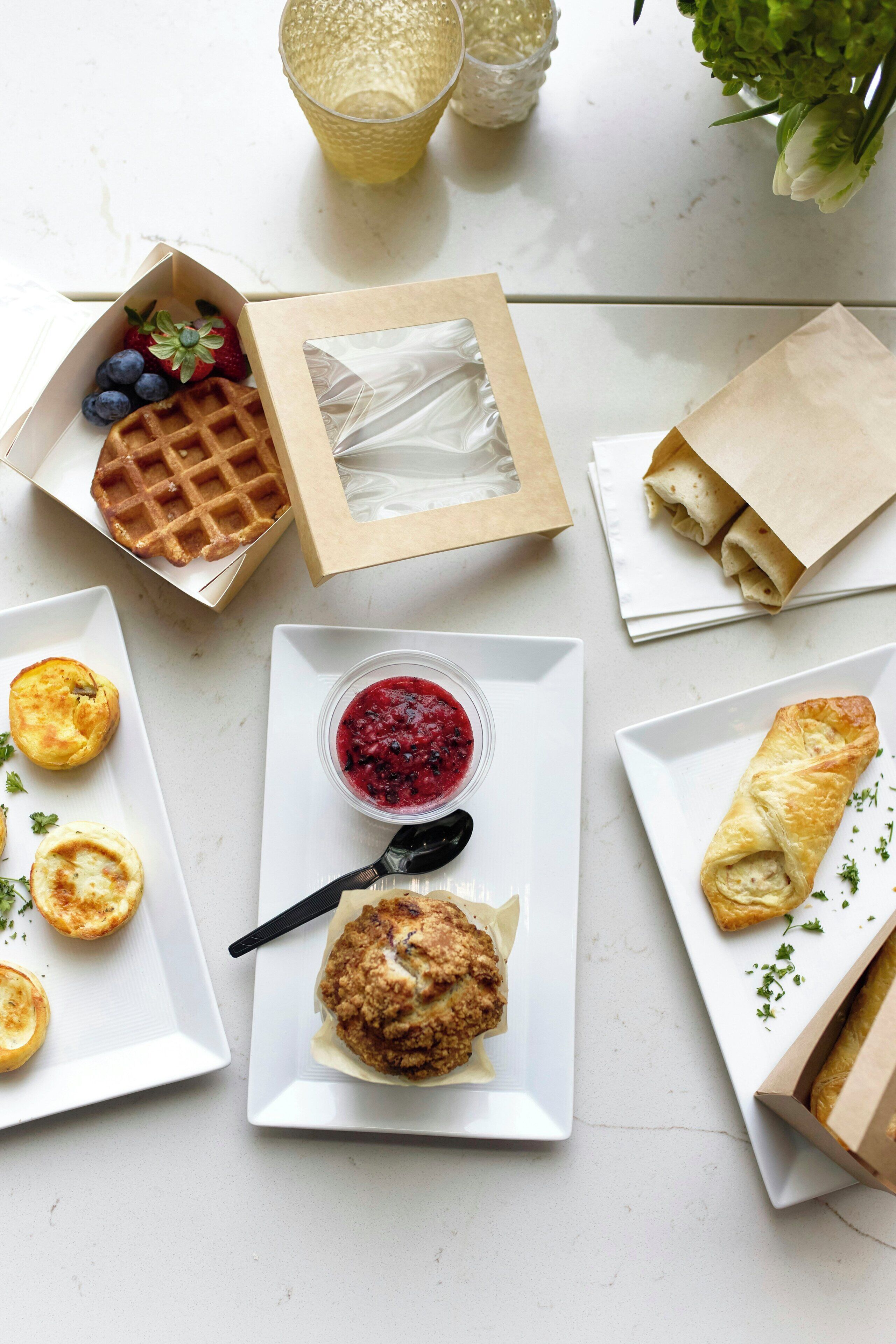 A table with various food items including waffles, pastries, and a bowl of berry compote.
