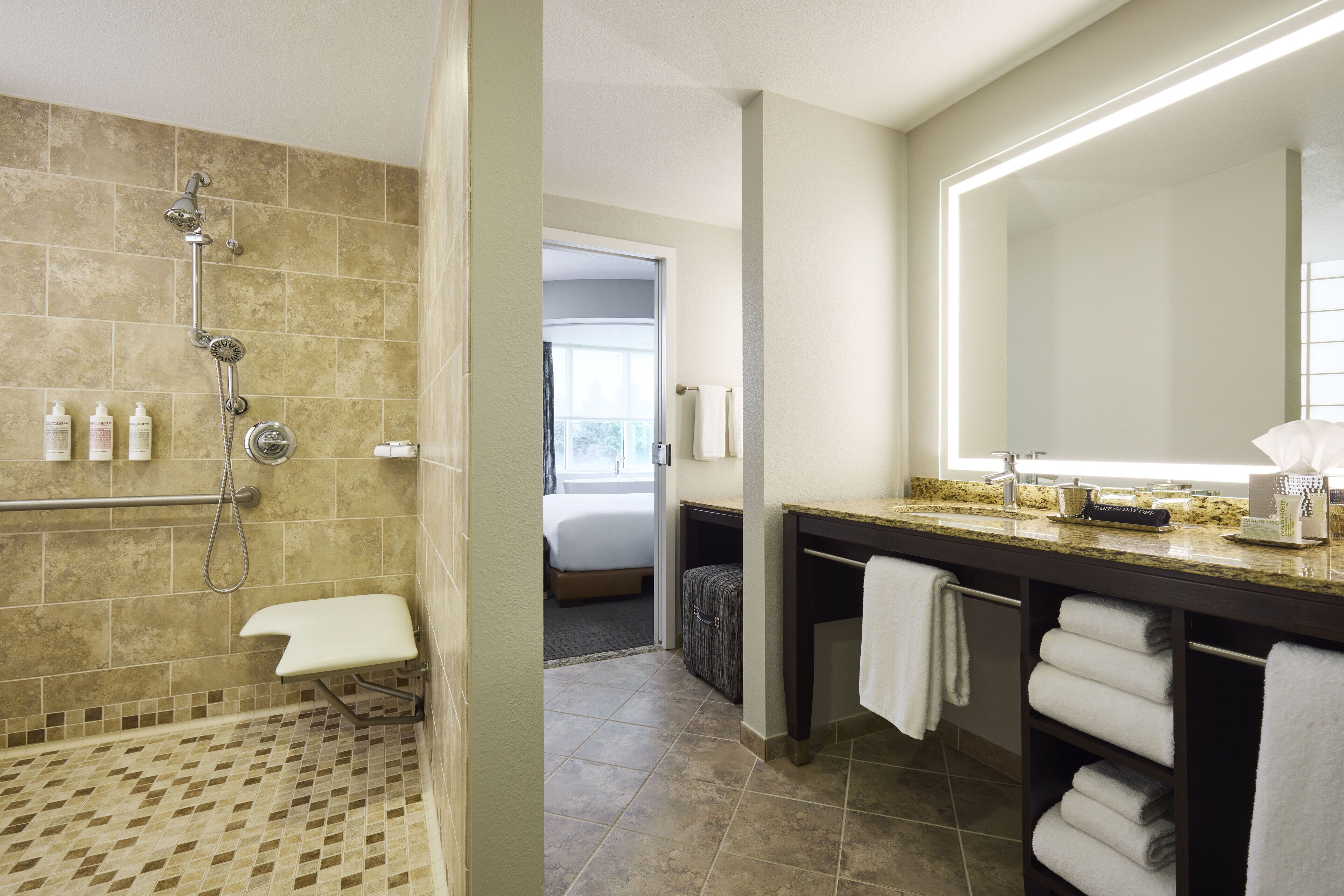 the grand den mobility-accessible suite with roll-in shower | bathroom | designer toiletries, hair dryer, bathrobes, slippers