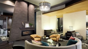A modern living room with a fireplace, leather sofas, and a chandelier.