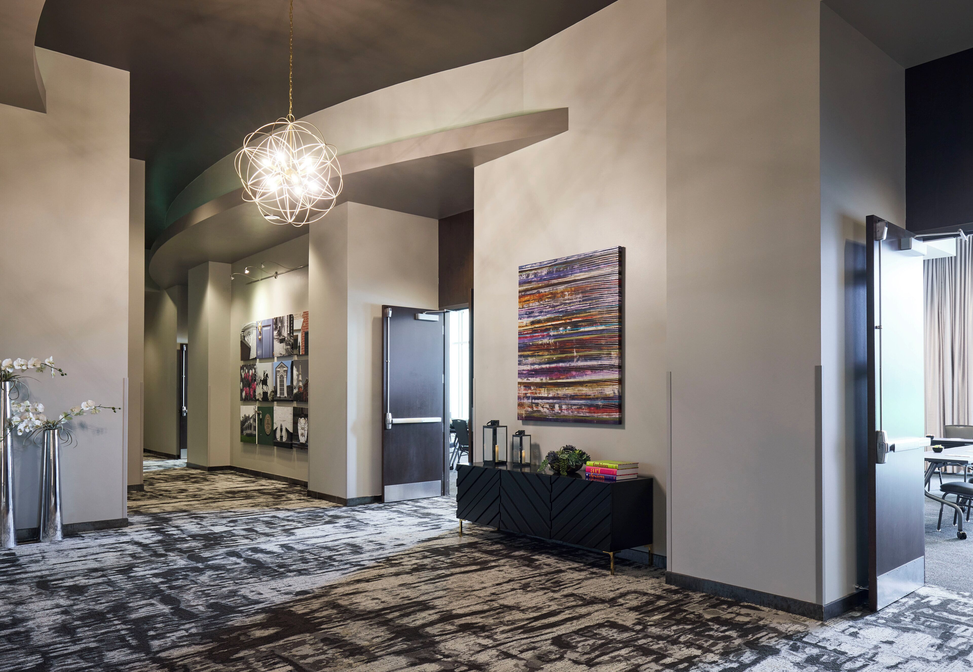 Un vestíbulo de hotel moderno con una consola negra, un cuadro abstracto grande y una alfombra estampada.