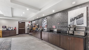 A modern kitchen with stainless steel appliances, a coffee station, and a large poster on the wall.