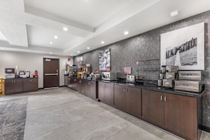 A modern kitchen with stainless steel appliances, a coffee station, and a large poster on the wall.