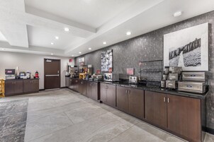 Una cocina moderna con electrodomésticos de acero inoxidable, una estación de café y un cartel grande en la pared.
