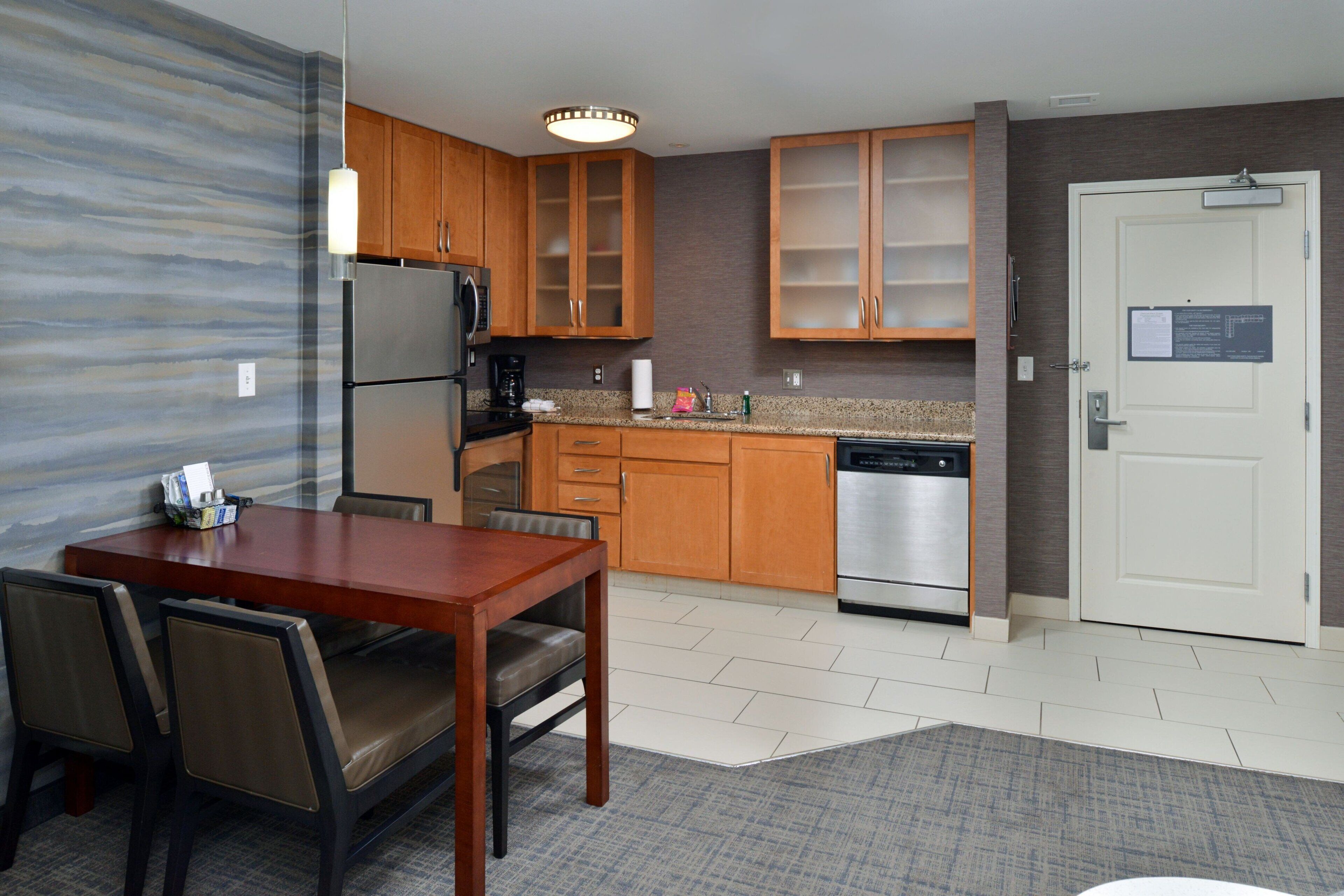A modern kitchen with wooden cabinets, a stainless steel refrigerator, and a dishwasher.