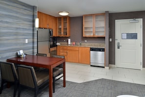 A modern kitchen with wooden cabinets, a stainless steel refrigerator, and a dishwasher.