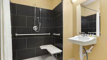 Un baño con ducha, un lavamanos blanco y un espejo.
