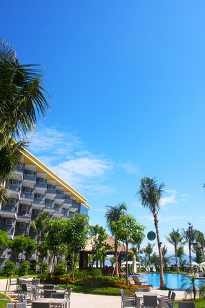 A resort with a swimming pool, outdoor seating, and a building with balconies.