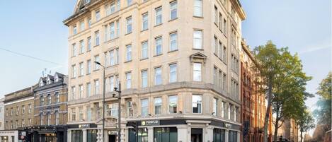 A multi-story hotel with a classic architectural style, featuring a corner entrance with a prominent sign.