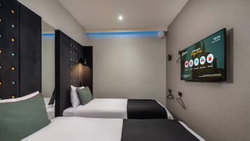 Ein Hotelzimmer mit zwei Betten, einem Fernseher an der Wand und Blick auf die Stadt.