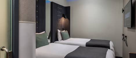 A hotel room with two beds, a flat-screen TV, and a mirror.