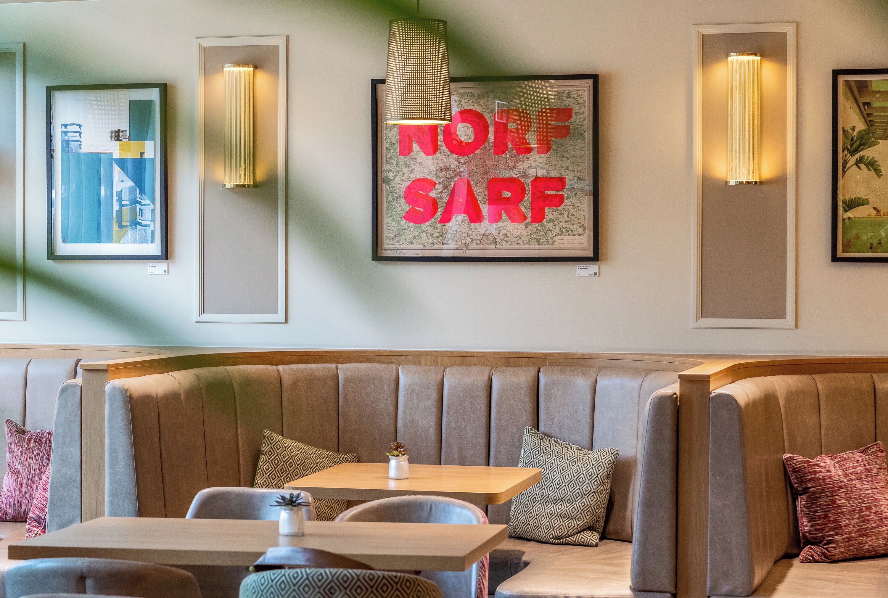 A modern interior with a seating area, framed artwork, and wall-mounted lighting.