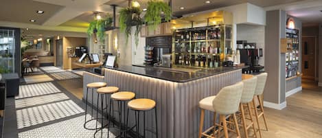 Eine moderne Bar mit einer Theke, Hockstühlen und einer Auswahl an Flaschen und Gläsern.