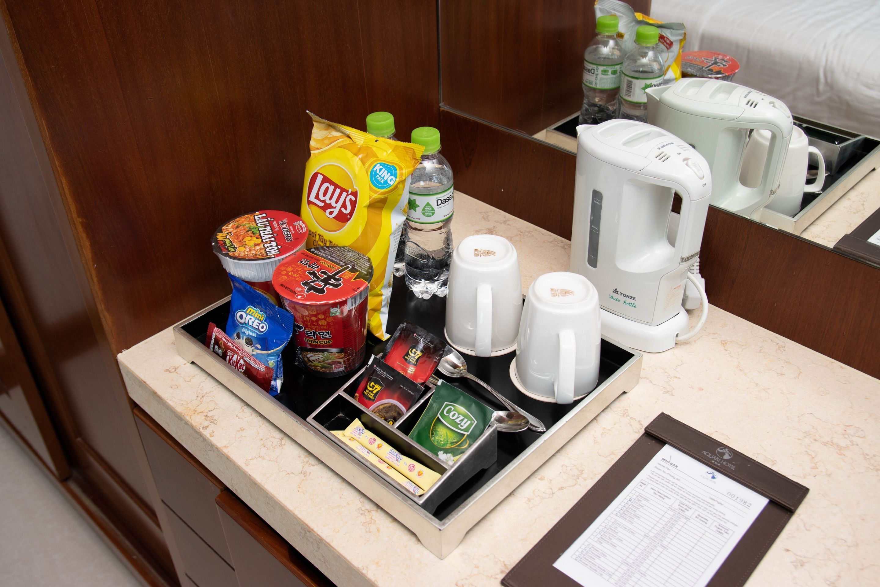 Un minibar de hotel con aperitivos, bebidas y equipo para preparar café.