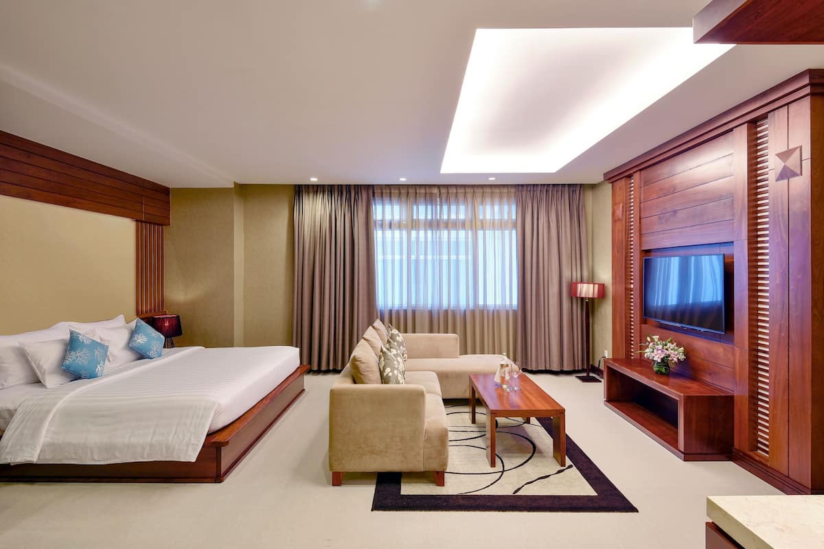 A hotel room with a bed, sofa, TV, and a desk.