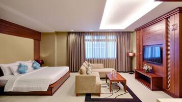 A hotel room with a bed, sofa, TV, and a desk.