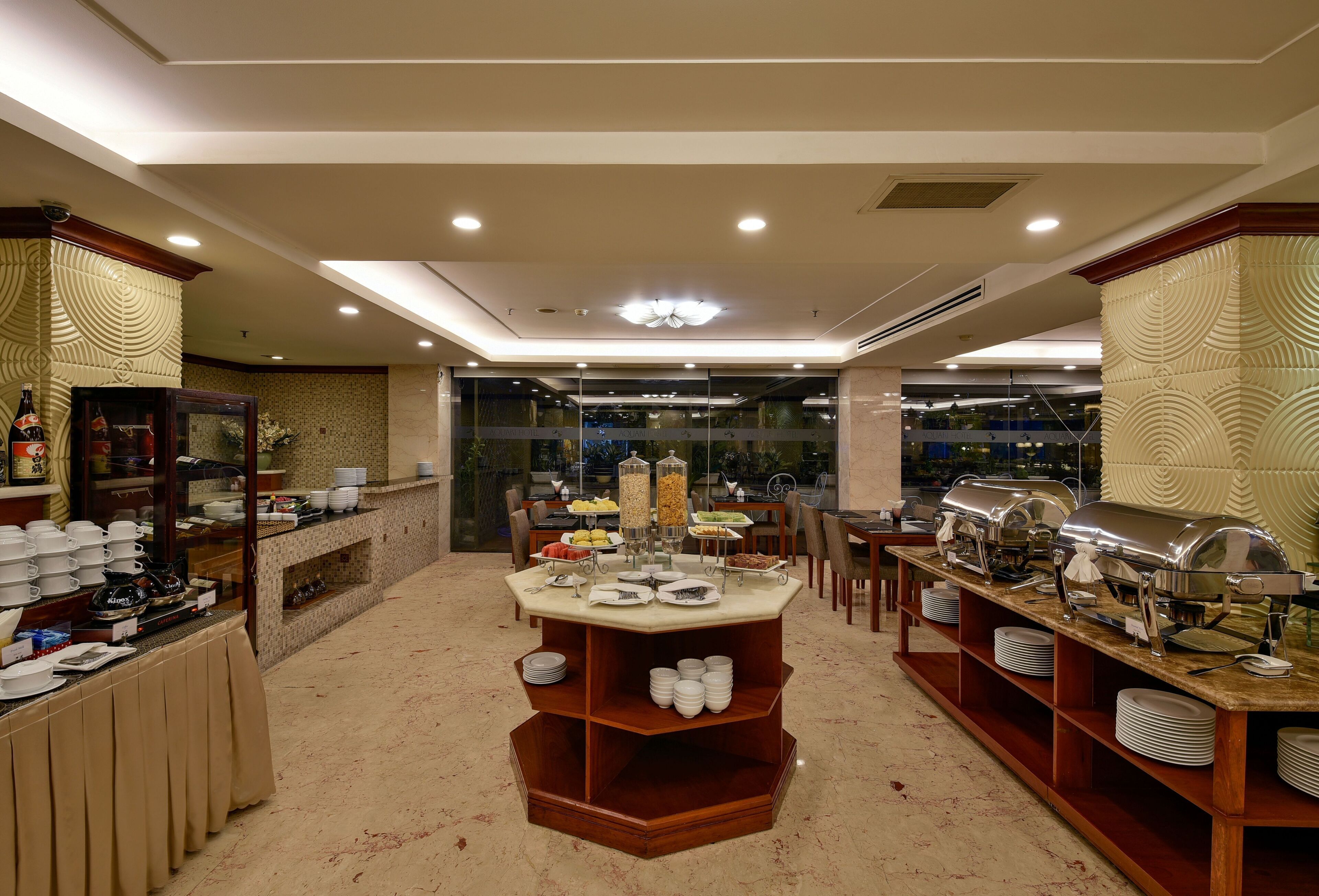 A buffet setup with multiple serving stations, a glass partition, and a variety of food items.