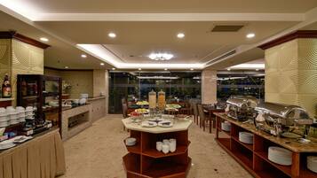 A buffet setup with multiple serving stations, a glass partition, and a variety of food items.