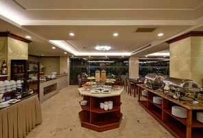 A buffet setup with multiple serving stations, a glass partition, and a variety of food items.